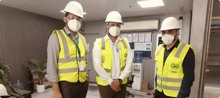 Environmental consultants wearing safety helmets conducting a site inspection at a landfill with a clipboard, discussing ISO 14001 compliance in Qatar.