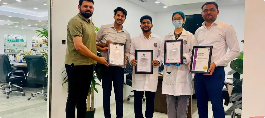 Team of professionals at a certified facility in Qatar proudly displaying their ISO 9001 certificates, supported by QDOT Consultancy.