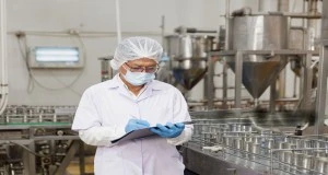 Food safety auditor inspecting production line during HACCP audit preparation in a food facility