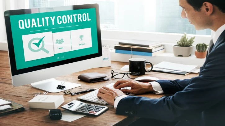 Business professional working on computer with quality control dashboard for ISO 9001 certification and consultancy.